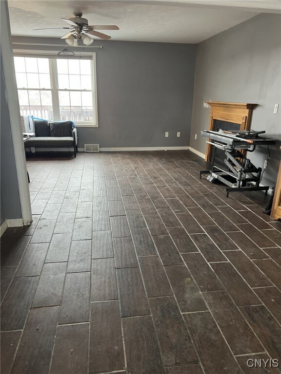 interior space featuring dark wood finished floors, visible vents, ceiling fan, and baseboards