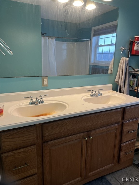 bathroom with double vanity, a shower with curtain, tile patterned flooring, and a sink