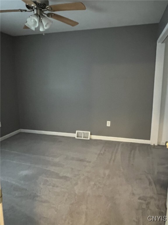 spare room with baseboards, visible vents, and ceiling fan