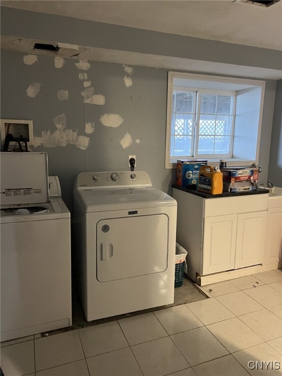 washroom featuring cabinet space, light tile patterned flooring, and independent washer and dryer