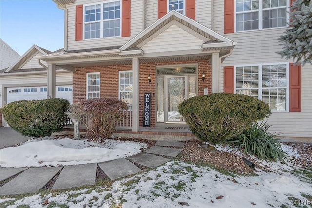 view of exterior entry with a garage and brick siding