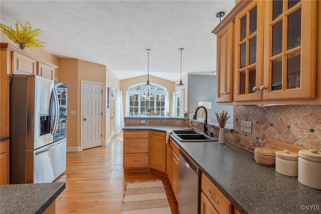 kitchen with lofted ceiling, a sink, appliances with stainless steel finishes, decorative backsplash, and dark countertops