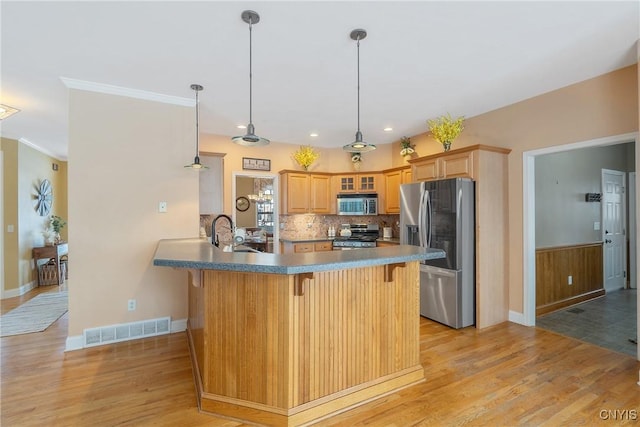 kitchen with light wood finished floors, stainless steel appliances, visible vents, glass insert cabinets, and a peninsula