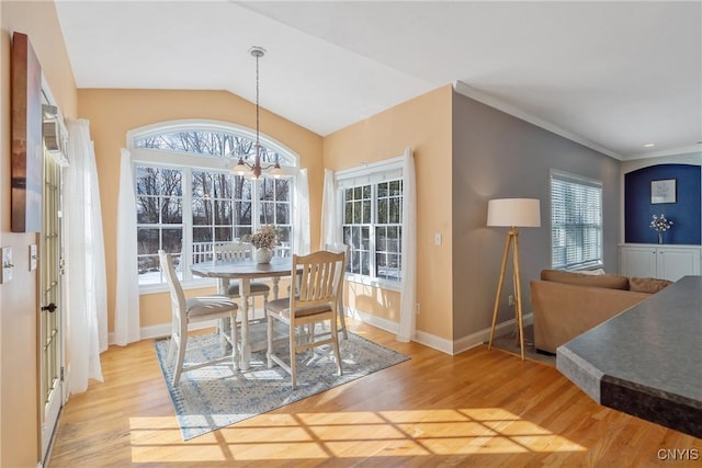 dining area with vaulted ceiling, light wood finished floors, baseboards, and an inviting chandelier