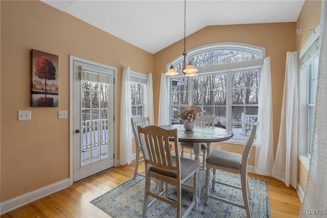 dining space with lofted ceiling, light wood-style floors, baseboards, and a chandelier