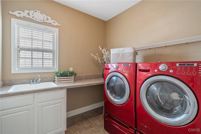 laundry area featuring cabinet space, baseboards, separate washer and dryer, and a sink