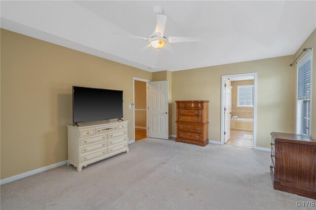 unfurnished bedroom with light carpet, ceiling fan, baseboards, and ensuite bathroom