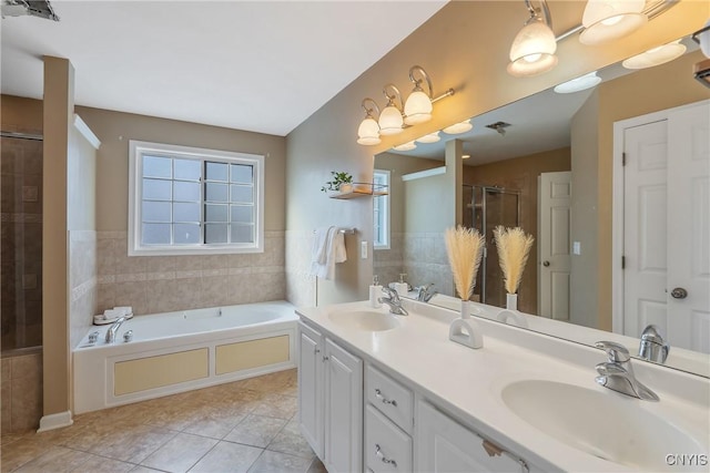 bathroom featuring a garden tub, a stall shower, a sink, and tile patterned floors