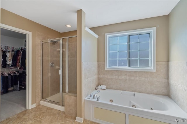 full bathroom featuring a shower stall, a tub with jets, a walk in closet, and tile patterned floors