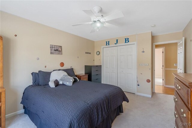 bedroom with baseboards, a ceiling fan, a closet, and light colored carpet