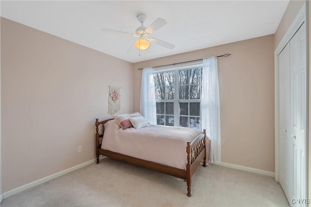 bedroom featuring baseboards, ceiling fan, a closet, and light colored carpet