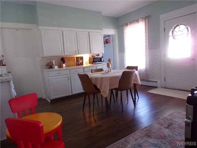 dining space featuring baseboard heating, dark wood-type flooring, and wainscoting