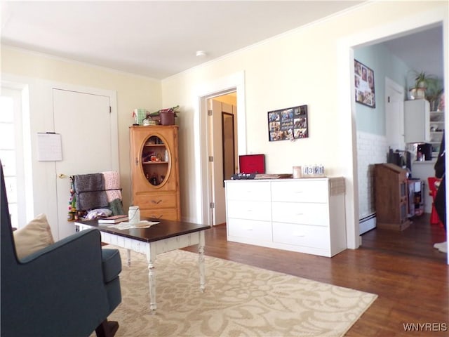 sitting room with a baseboard heating unit, ornamental molding, and dark wood-type flooring