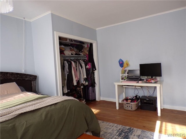 bedroom with crown molding, a closet, baseboards, and wood finished floors