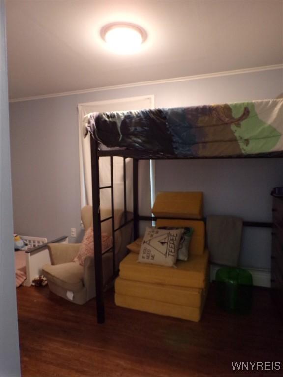 bedroom featuring wood finished floors and crown molding