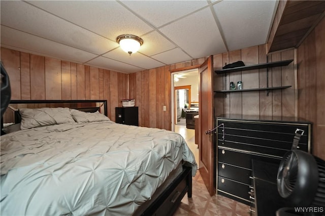 bedroom featuring wood walls and a paneled ceiling