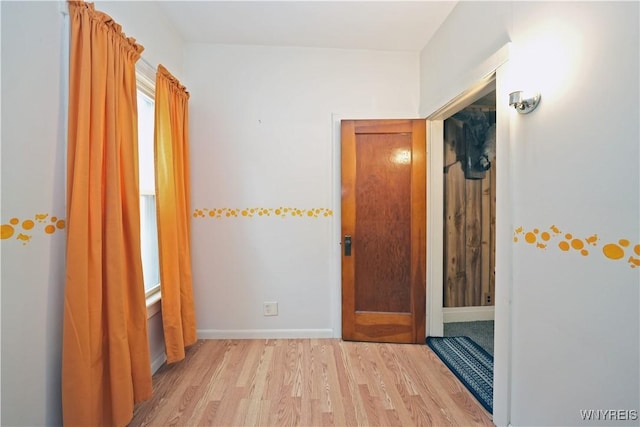 hall with light wood-style flooring and baseboards