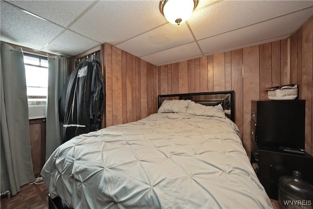 bedroom with cooling unit, wood walls, and a paneled ceiling