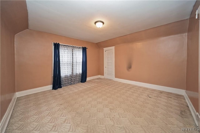 unfurnished room featuring baseboards and vaulted ceiling