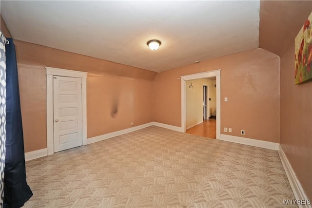 spare room featuring lofted ceiling, carpet floors, and baseboards