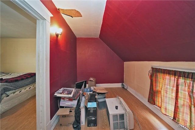 interior space with vaulted ceiling, baseboards, and wood finished floors