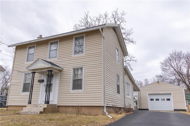 view of front of home featuring entry steps, an outdoor structure, driveway, and a detached garage