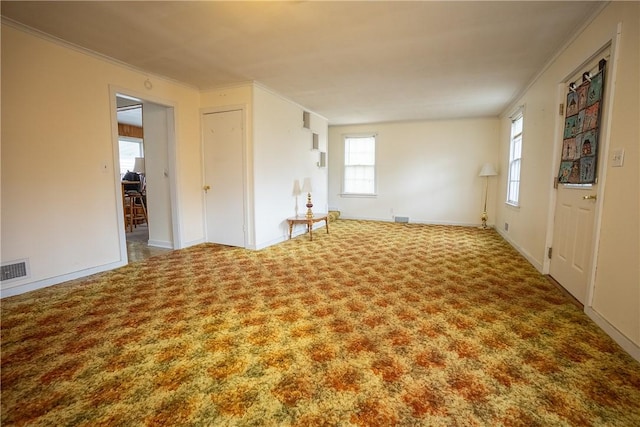 unfurnished room with carpet floors, visible vents, ornamental molding, and baseboards