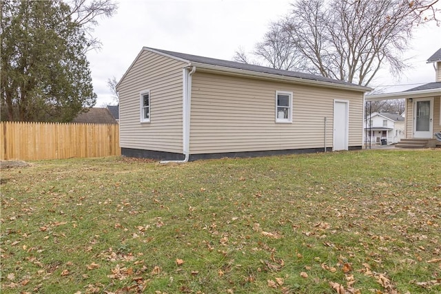 view of side of home featuring entry steps, fence, and a lawn