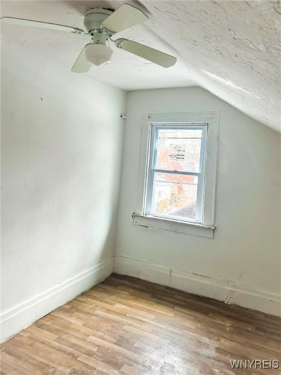 bonus room with light wood-type flooring, baseboards, a ceiling fan, and lofted ceiling