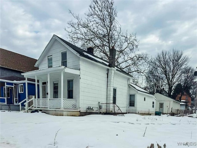 view of front facade with covered porch and a chimney