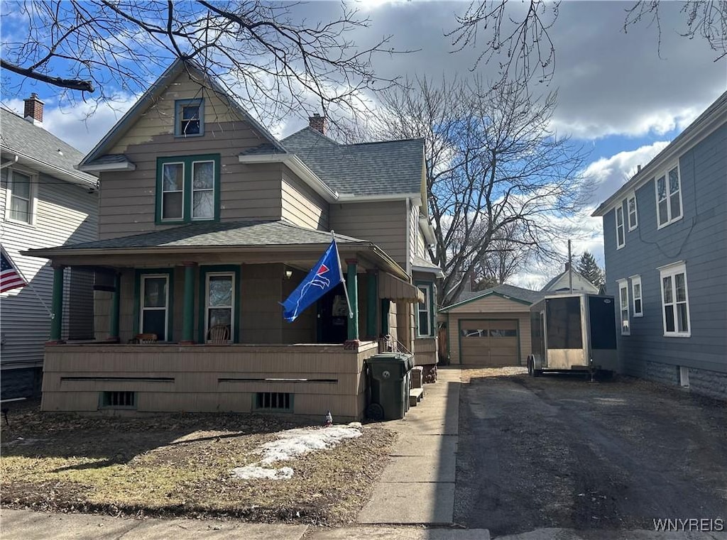 view of side of property featuring a shingled roof, a porch, a garage, driveway, and an outdoor structure