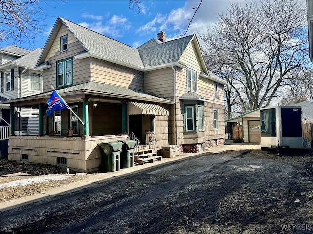 view of front of house with a garage, a chimney, an outdoor structure, and roof with shingles