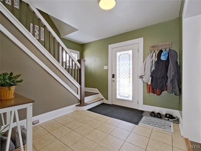 foyer entrance with stairs, baseboards, and tile patterned floors