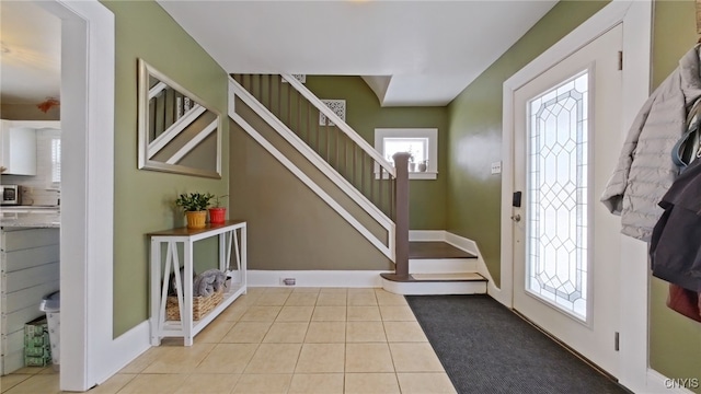 entrance foyer featuring light tile patterned floors, stairs, and baseboards