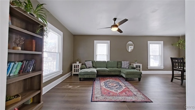 living area with dark wood-style floors, baseboards, and a ceiling fan