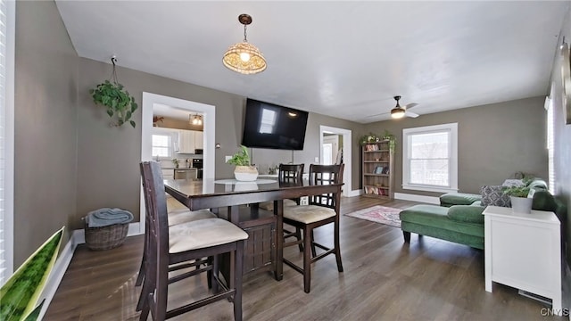 dining space with wood finished floors, a ceiling fan, and baseboards