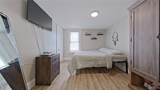 bedroom with light wood finished floors and baseboards