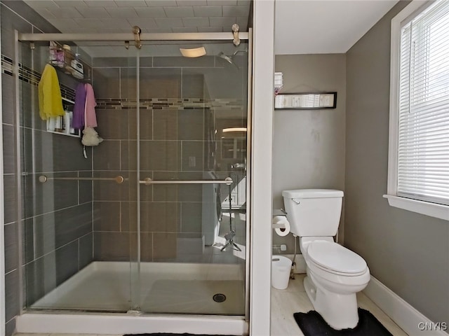 bathroom with toilet, a shower stall, and baseboards