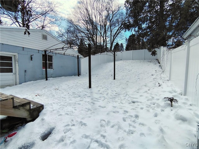 snowy yard with a garage and a fenced backyard