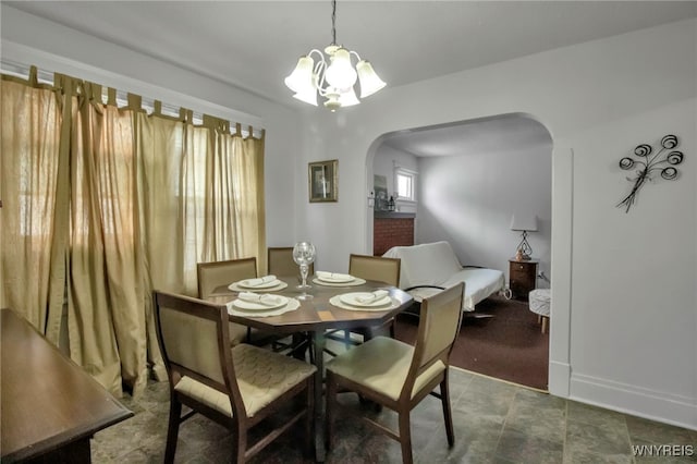 dining room featuring arched walkways, baseboards, and an inviting chandelier