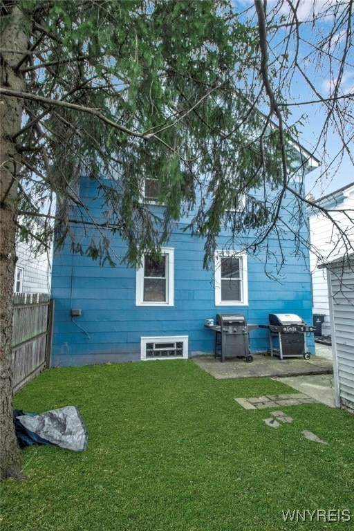 back of property with fence and a lawn