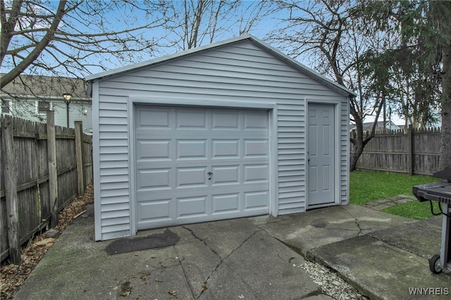 detached garage featuring fence and driveway