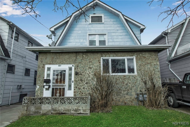 dutch colonial featuring stone siding, a front lawn, and a gambrel roof