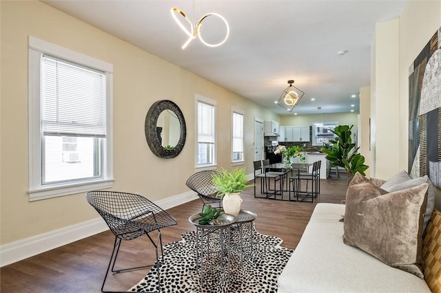 living area featuring dark wood-style floors, baseboards, and an inviting chandelier