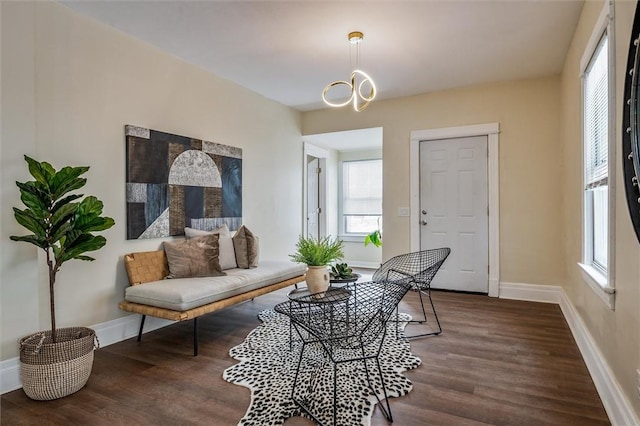 sitting room featuring baseboards, a chandelier, and wood finished floors