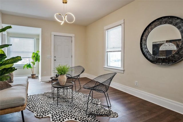 interior space featuring dark wood-style flooring, an inviting chandelier, and baseboards