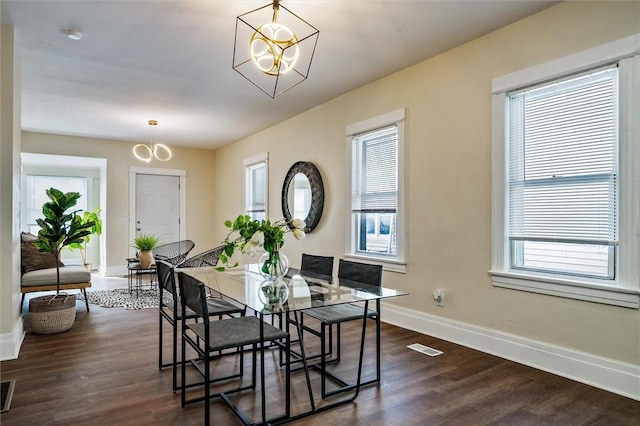 dining room featuring baseboards, a healthy amount of sunlight, dark wood-style flooring, and an inviting chandelier