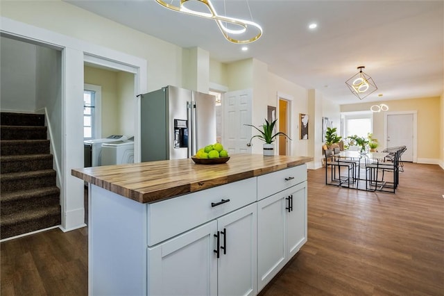 kitchen featuring wood counters, white cabinets, a wealth of natural light, stainless steel fridge, and washing machine and clothes dryer