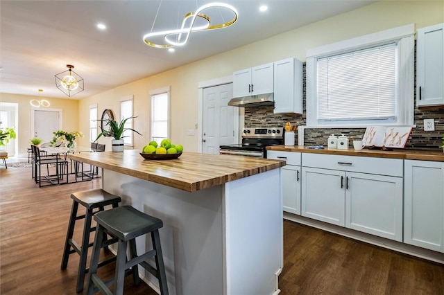 kitchen featuring under cabinet range hood, stainless steel electric range oven, wooden counters, and decorative backsplash