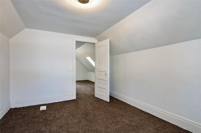 additional living space featuring lofted ceiling, dark carpet, and baseboards